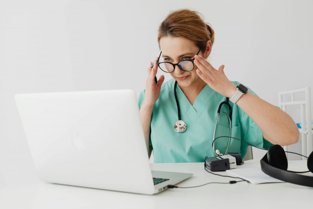 Medical professional conducting a virtual consultation with a laptop and stethoscope.