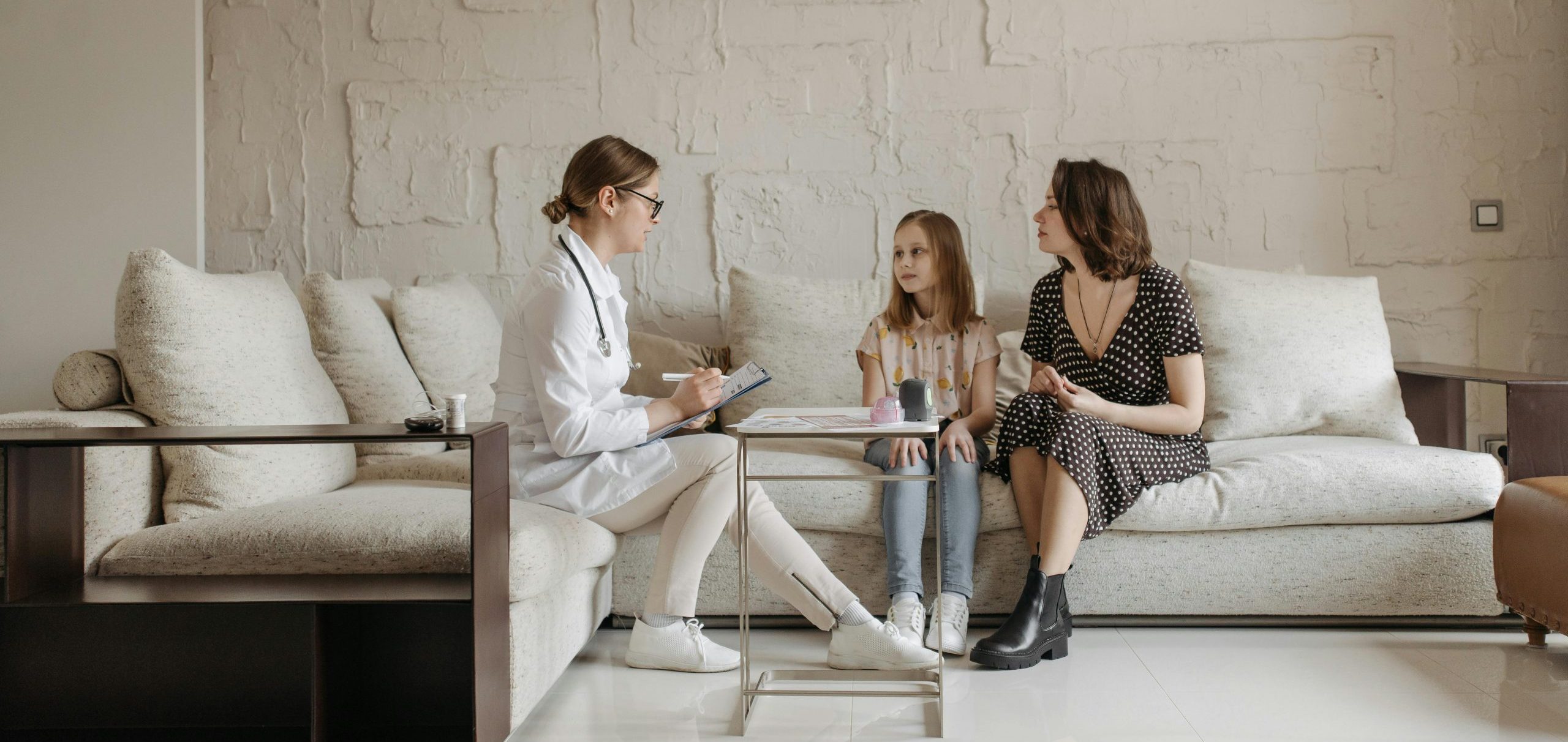 Doctor consulting a mother and daughter in a cozy indoor setting.